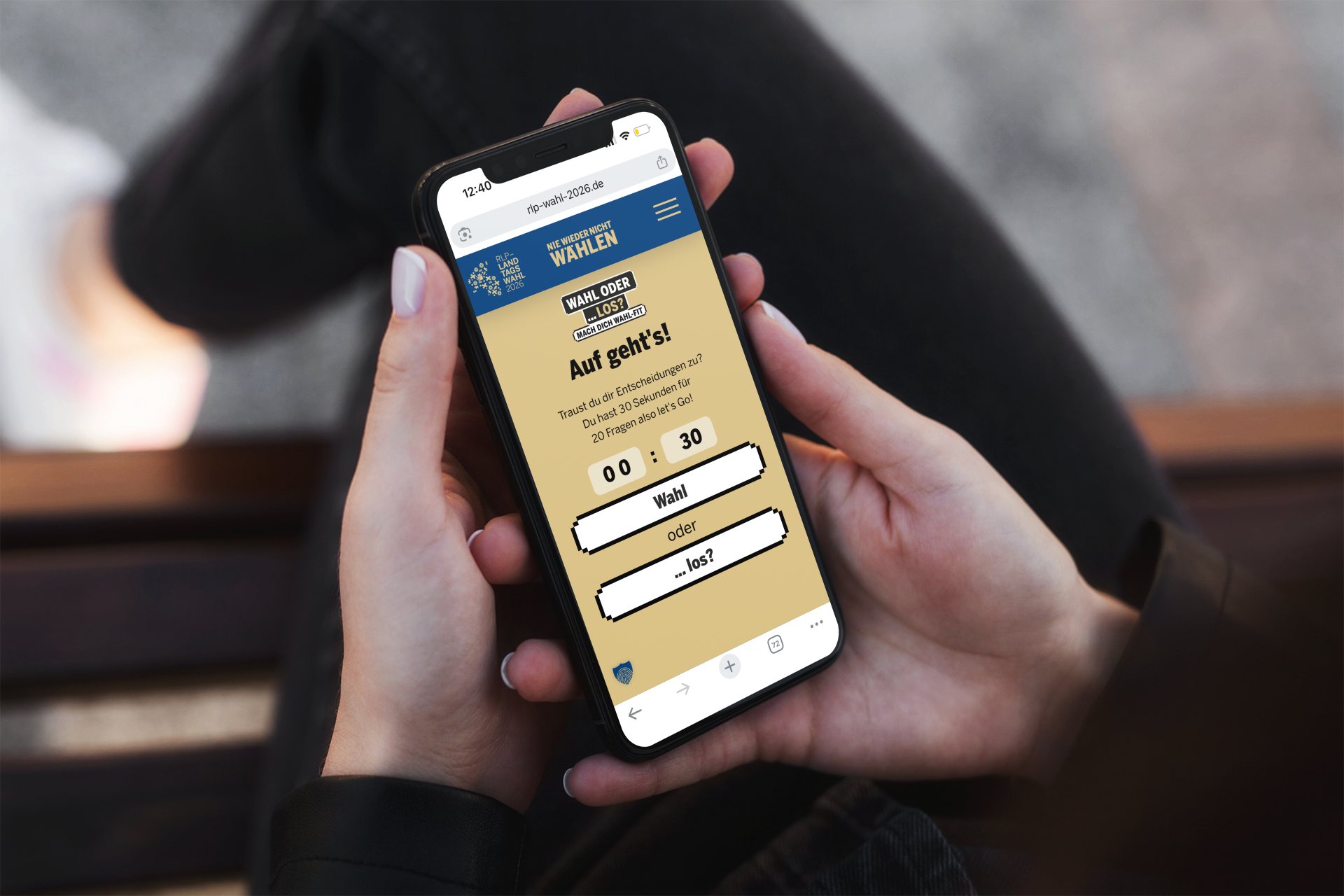 Eine Person hält ein Smartphone in den Händen. Auf dem Bildschirm ist ein Spiel zur Wahl zu sehen. Das Spiel heißt: „Wahl oder … los?“. Man soll schnell Entscheidungen treffen. Das Bild zeigt: Wählen kann man üben.