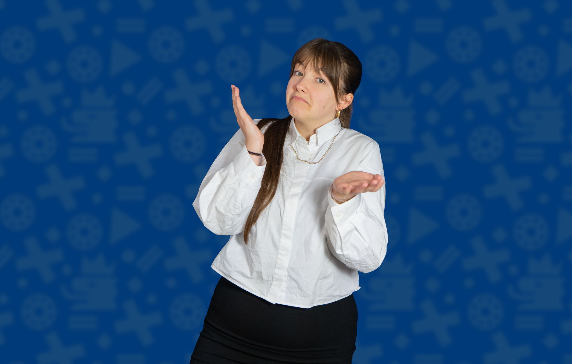 Eine junge Frau steht vor einem blauen Hintergrund. Sie trägt eine weiße Bluse und einen dunklen Rock. Sie hebt beide Hände und schaut unsicher. Das zeigt: Entscheiden ist manchmal schwer.